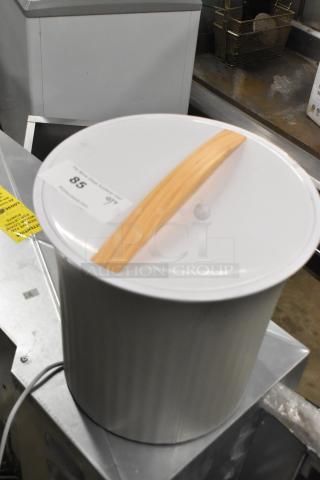 Towel warmer with wooden handle, 115 volts, 1 phase, in good condition. Features a metal body with a white lid.