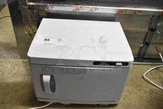 White towel warmer cabinet, brand Wuissynab, 120 volts, 1 phase. Good condition with auction label "89."