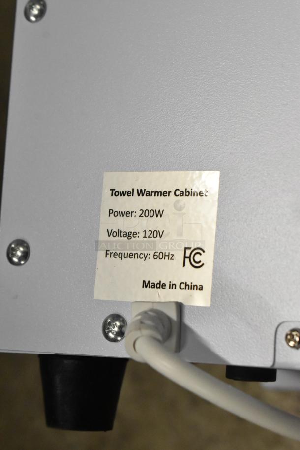Towel Warmer Cabinet, 120V, 200W, 60Hz, FCC certified. Label indicates "Made in China." Visible screws and power cord.