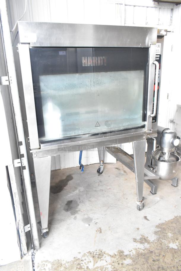 Hardt Inferno 3500 stainless steel rotisserie oven, natural gas, skewers, on metal legs with commercial casters; good condition.