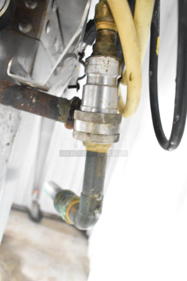 Close-up of gas connection on Hardt Inferno 3500 rotisserie oven showing metal fittings and hoses. Some wear visible.