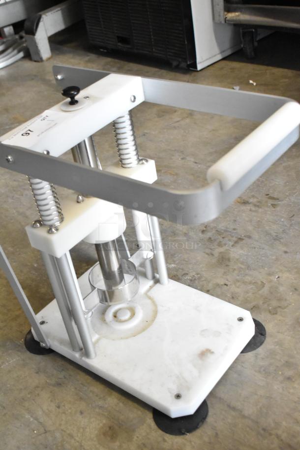 Countertop pineapple corer with sturdy metal frame, spring-loaded press, and gripping handle. Appears in used condition.