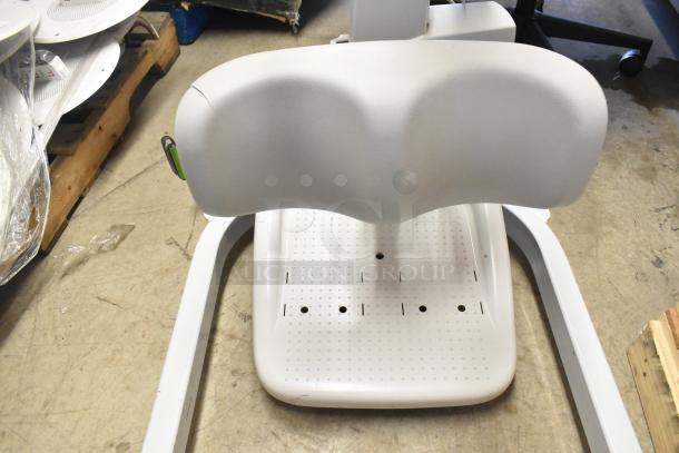 Sabina II Sit To Stand Patient Lift in used condition. Features padded support and wheeled base. Some surface wear visible.