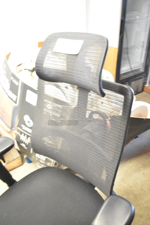 Black office chair on casters with mesh backrest, ergonomic design, adjustable armrests, and fabric seat. Good condition.