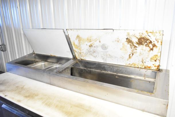 Avantco 178PICL2 stainless steel pizza prep table with open lids, showing some wear, on commercial casters. 115V, 1 phase.