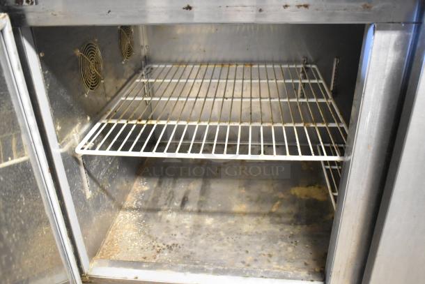 Avantco 178PICL2 stainless steel pizza prep table interior, showing wire rack shelf, moderate wear, and dual fans. 115V, 1 phase.