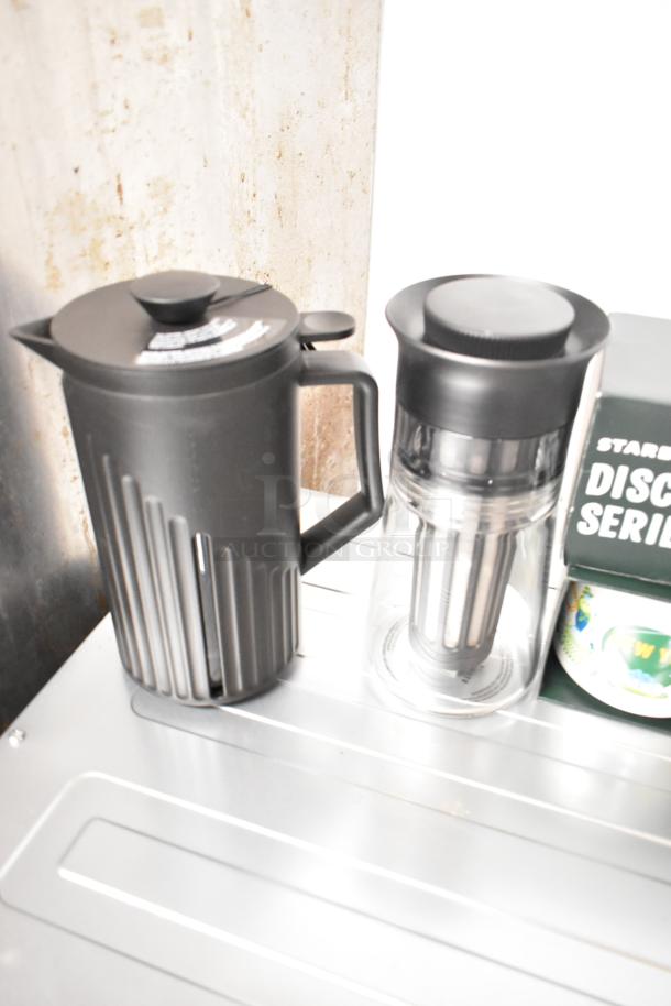 Lot of items featuring a black insulated pitcher, clear pitcher with filter, and Discovery Series mug, all in good condition.