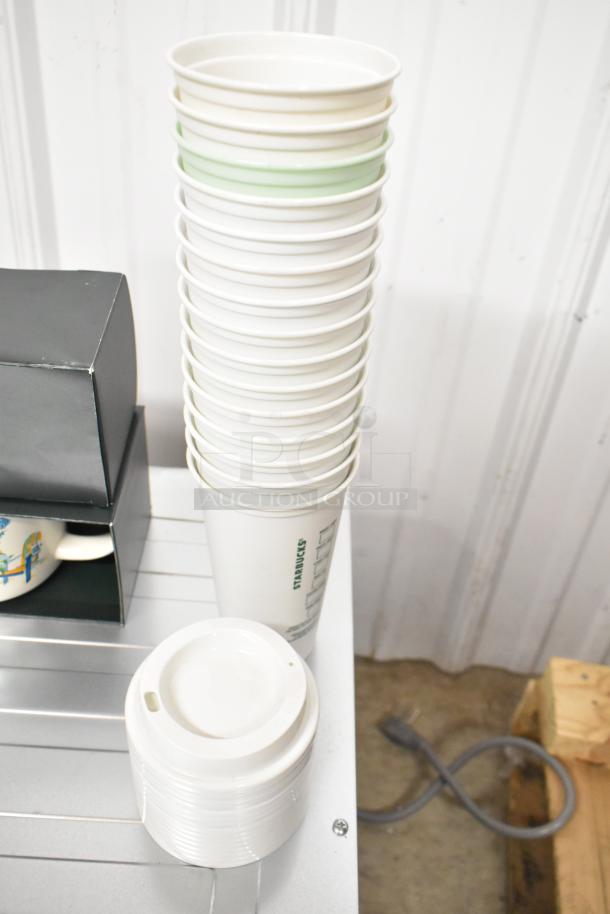 Lot of various items including a stack of Starbucks coffee cups, a Discovery Series mug in box, and white cup lids, good condition.