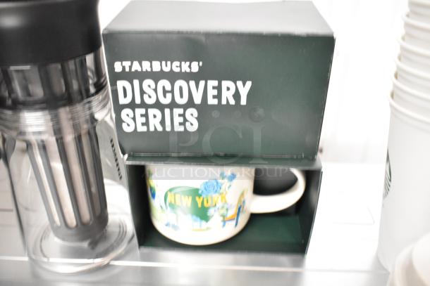 Starbucks Discovery Series New York mug in box, clear pitcher beside it, multiple empty cups stacked, good condition.