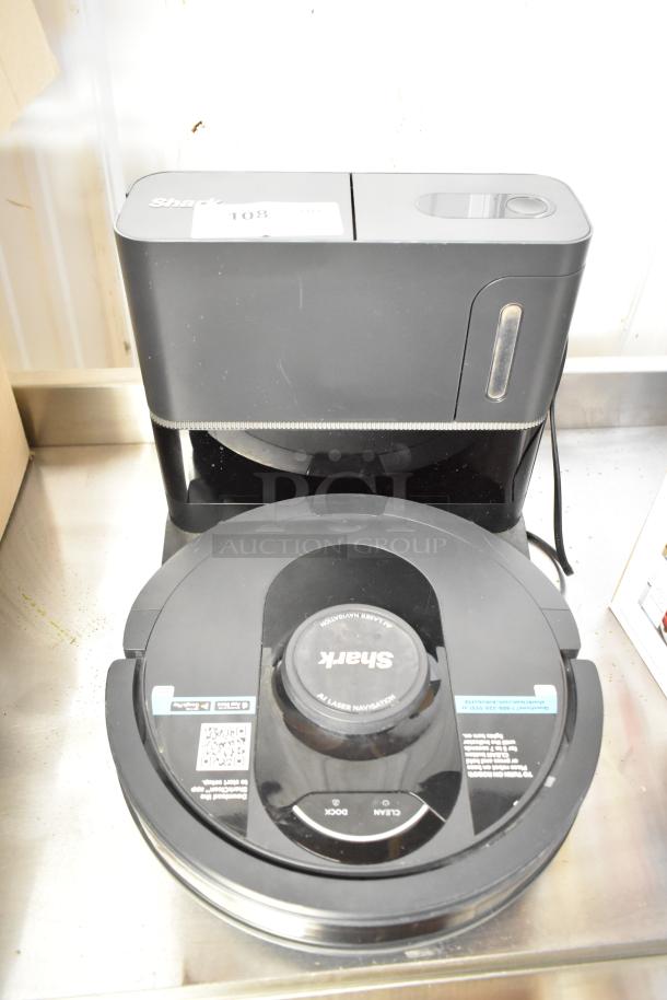 Shark robot vacuum cleaner with docking station, 120 volts, 1 phase, in used condition. Visible control labels and branding.