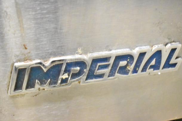 Imperial stainless steel convection oven close-up showing brand logo, viewed on a slightly used metal surface.