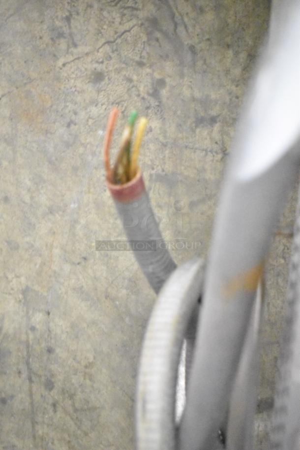 A loose frayed electrical cable with exposed wires, indicating potential repair needs. Background of concrete floor.