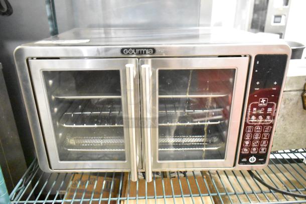 Gourmia GTF7660 digital air fryer oven in metal finish; visible control panel, dual doors, three interior racks, 120 volts, 1 phase.