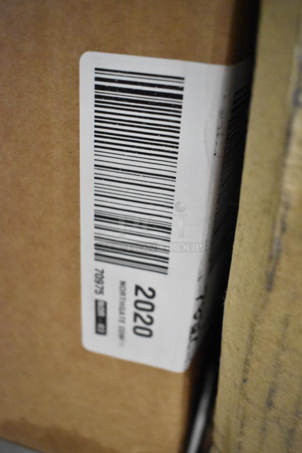 Close-up of a cardboard box with a barcode and printed numbers, part of an auction lot including various items like To Go containers and Purell wipes.