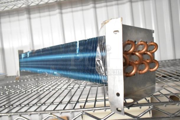 Brand new scratch and dent evaporator coil with copper tubing, blue aluminum fins, and minor surface imperfections.