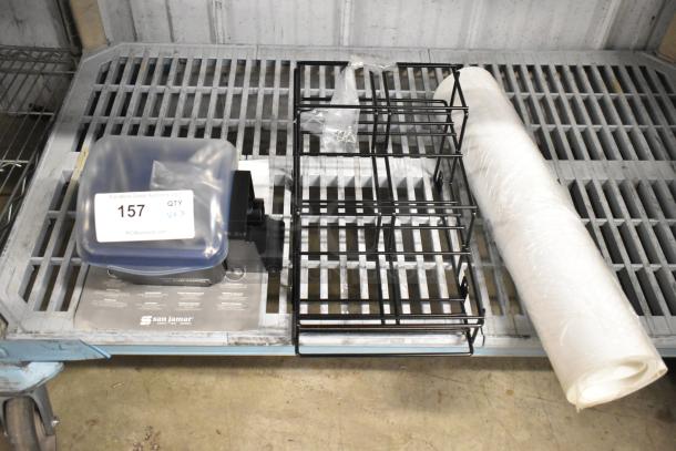 San Jamar poly topping rail, black metal stand, and roll of white material. Auction tag with lot number 157 visible.