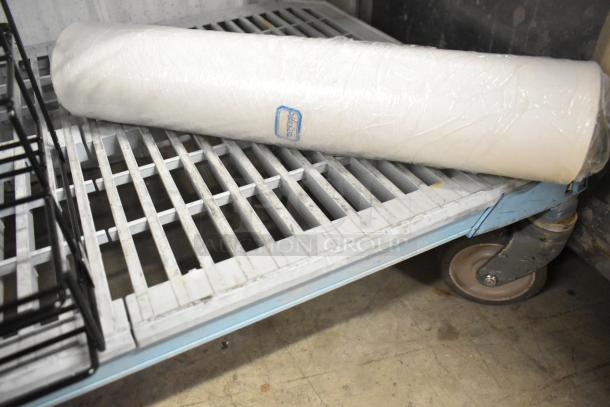 Roll of white material on a metal cart with caster wheels, part of a lot including a San Jamar poly topping rail and black stand.