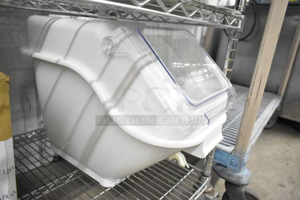 White poly ingredient bin with clear lid on metal shelf.  Holds bulk ingredients. Appears in good condition.