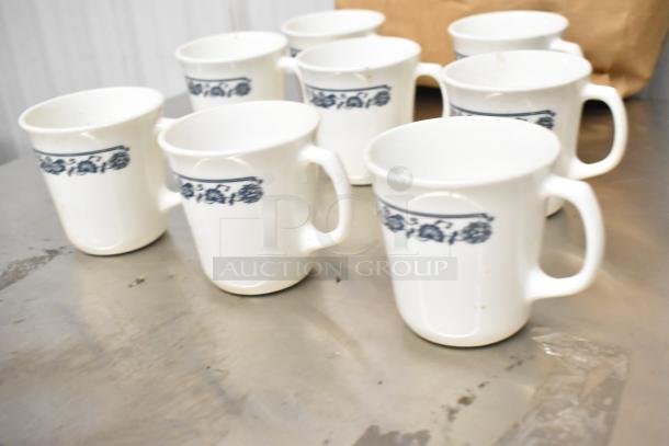 Eight white ceramic mugs with blue floral patterns, slightly worn condition, auction lot.