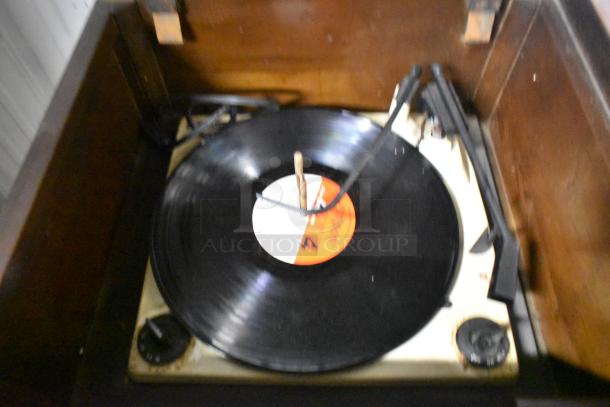 Victrola RCA Victor 67V1 record player in wood-pattern counter. Visible controls and spinning record. Classic design.