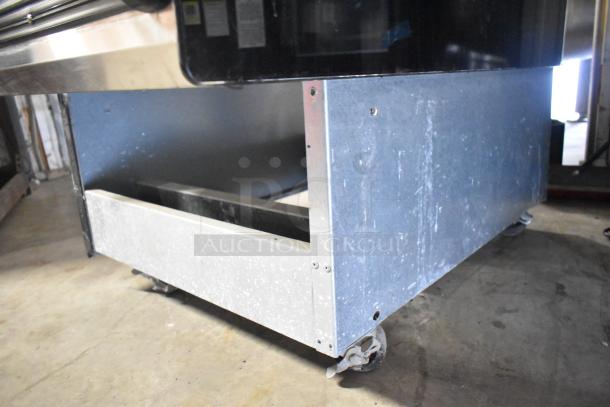 BKI HSS2-4T metal commercial reach-in hot merchandiser on casters. Features 208 volts, 1 phase. Visible metal casing, good condition.