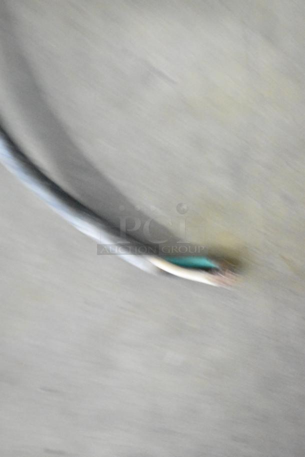 Blurry image showing a cable on a gray surface, details are unclear.
