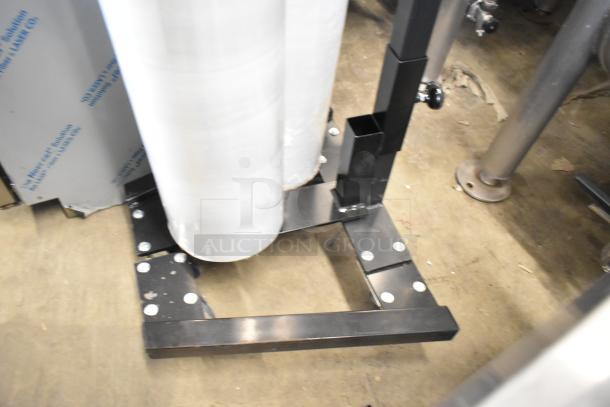 Fantom Full Web Manual Stretch Wrapper, black frame, dual roll holders, visible screws, stored indoors on concrete floor.