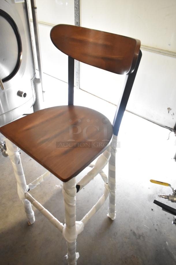 Brand new wooden bar height chair with scratch and dent, features a brown seat and backrest on black metal frame.