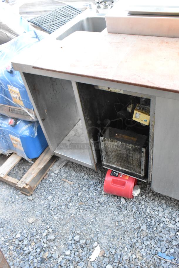 Stainless steel commercial pizza prep table with built-in sink bay, 115 volts, 1 phase, showing interior shelving and components.