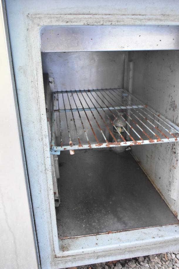 Stainless steel commercial pizza prep table with built-in sink bay, 115V, 1 phase, interior view showing rusted wire rack.