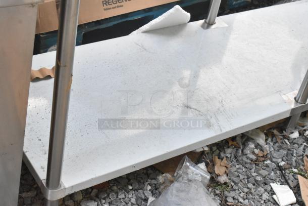 Regency 600TSB3084S stainless steel commercial table with metal under shelf, shows surface wear and signs of use.