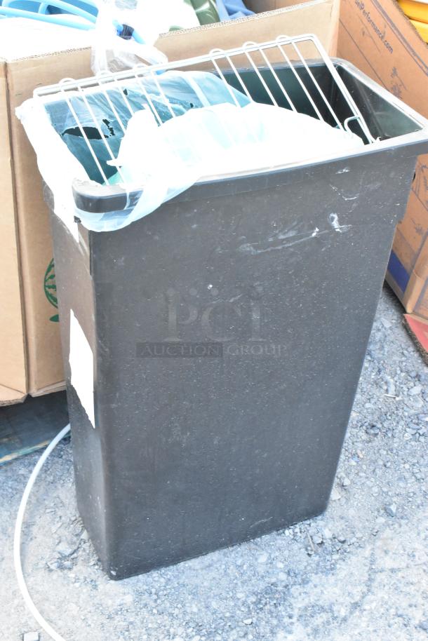 Black Poly Slim Jim trash can with contents, featuring a wire rack and a plastic bag. Some wear visible on exterior.
