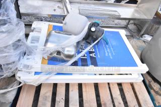 Five various items including A-frame sidewalk signs and Xcelerator hand dryer, stacked on a pallet, some wrapped in plastic.