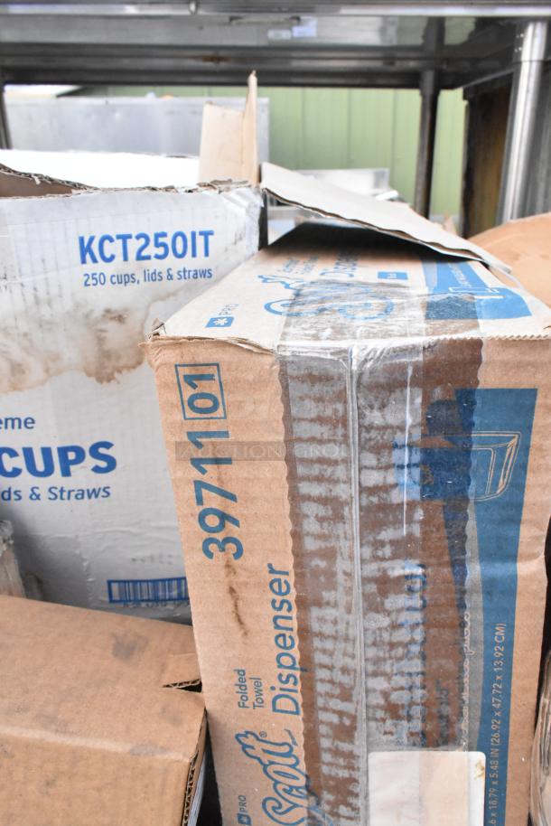 Boxes labeled "Scott Folded Towel Dispenser" and "250 Cups, Lids & Straws," showing new condition, slight box wear.