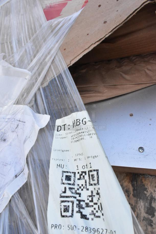 Brand new stainless steel table with minor scratches and dents, shown with packaging and shipping label indicating shipment details.