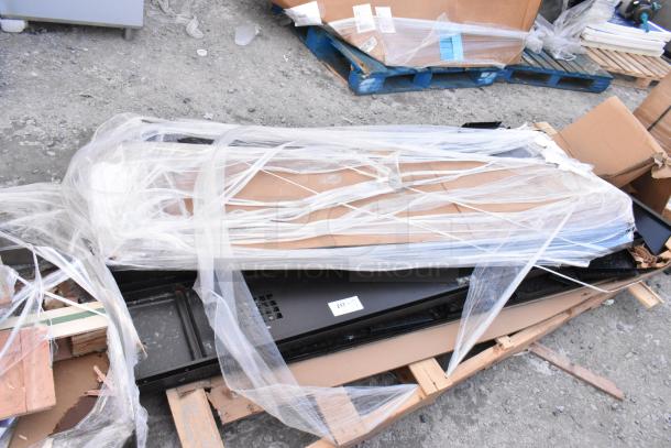 Brand new black metal locker system with minor scratches and dents, wrapped in protective plastic on a pallet.