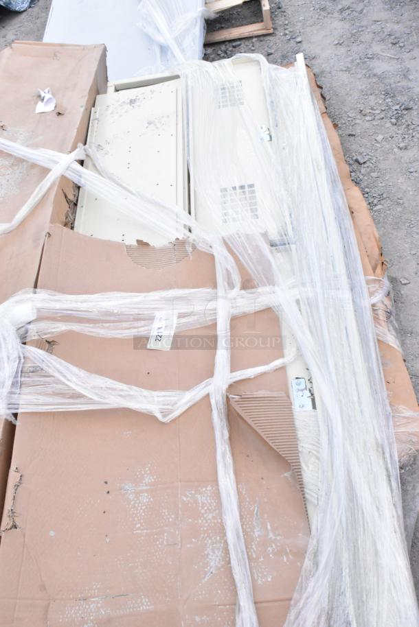 Tan metal locker system, wrapped in plastic with cardboard packaging. Visible vented doors, minor wear. Auction lot 221 tag attached.