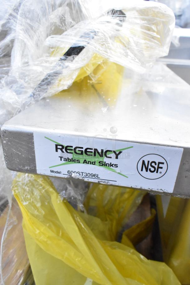 Brand new Regency 600ST3096L stainless steel table with a 16x20x12 sink, showing tags and slight dents, wrapped in plastic.