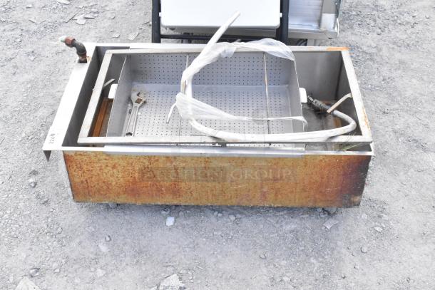 Metal grease trap on commercial casters, features rusted exterior, perforated tray. Used condition, no visible branding.
