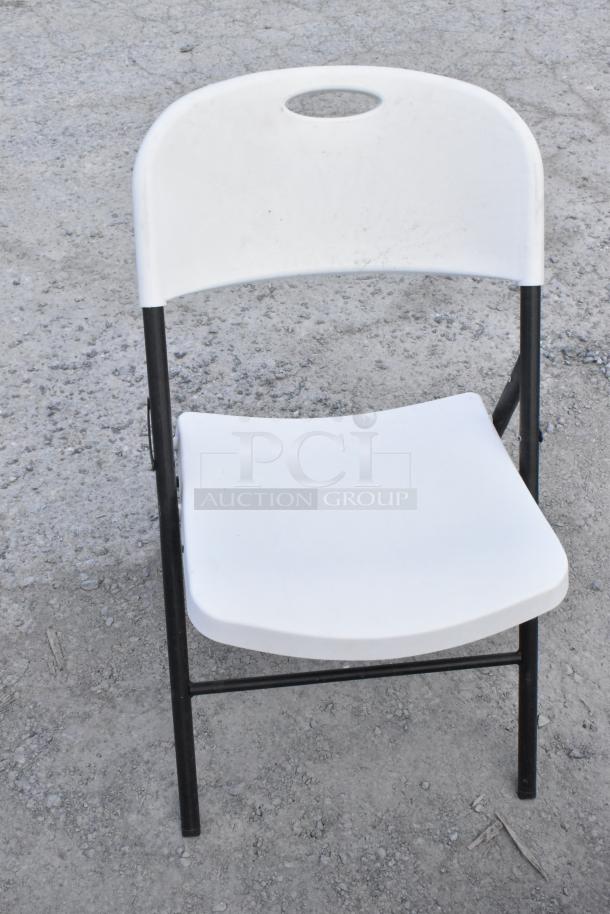 White poly and metal folding chair, fair condition, black frame, textured seat and backrest, suitable for indoor/outdoor use.