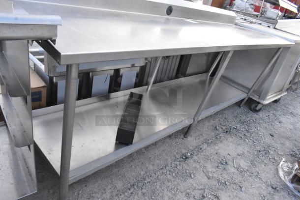 Stainless steel table with metal under shelf and backsplash, used condition, sturdy construction ideal for commercial use.