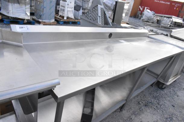 Stainless steel table with metal under shelf and backsplash, in good condition; features include reinforced legs and durable surface.