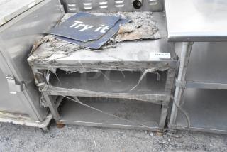 Stainless steel equipment stand with wear and damage, featuring a "Try it" sign. Tag labeled "230" states quantity of 1.