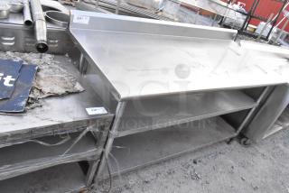 Stainless steel commercial table with two under shelves and back splash, used condition, label indicates item 230/231.