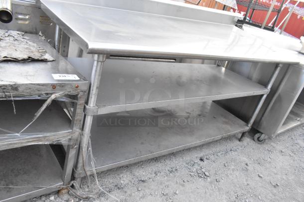 Stainless steel commercial table with 2 under shelves and backsplash, used condition, sturdy construction, ideal for kitchens.