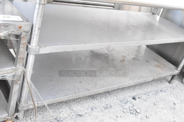 Stainless steel commercial table with two under shelves and backsplash, used condition, suitable for kitchen or restaurant use.