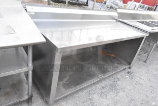 Stainless steel commercial table with under shelf and back splash, in good condition, ideal for kitchen use.