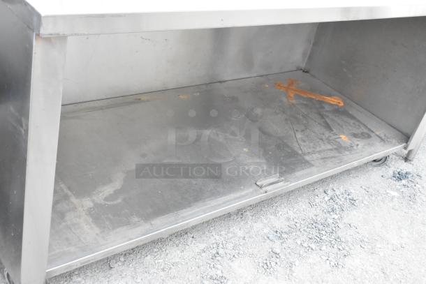 Stainless steel commercial table with under shelf, back splash, visible wear and rust, ideal for restaurant use.