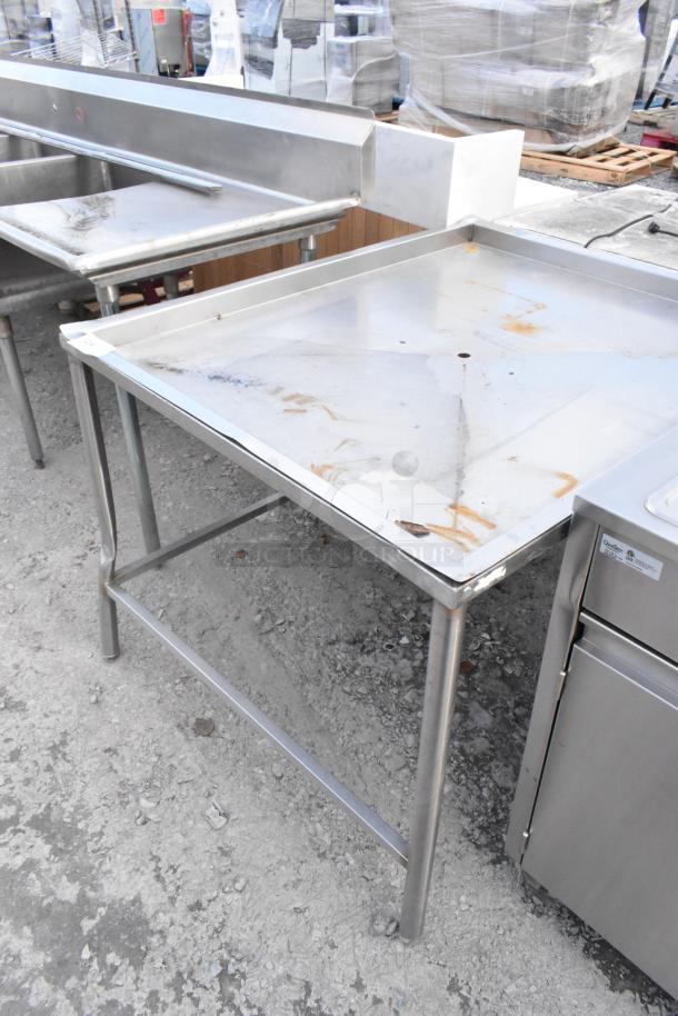Metal draining table with raised edges, used condition, visible stains and rust spots.
