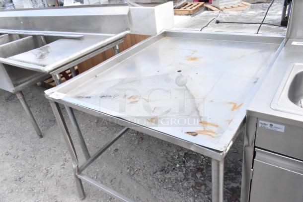 Stainless steel metal draining table in used condition, showing some rust and wear, suitable for industrial use.